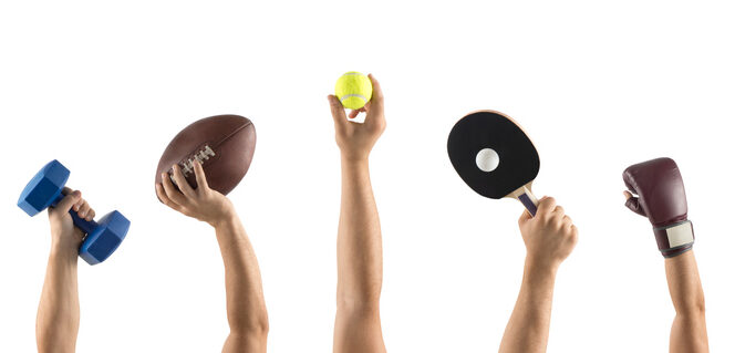 Fünf Hände halten Sportgegenstände in den Händen (Hantel, Football, Tennisball, Tischtennisschlaeger mit Ball, Boxhandschuh).
