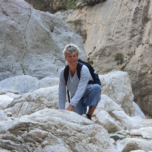Babsi in der Hocke, umgeben von grauen Felsen.