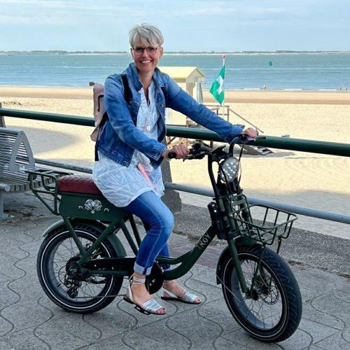 Linda sitzt entspannt auf dem Fahrrad auf der Strandpromenade in Holland.