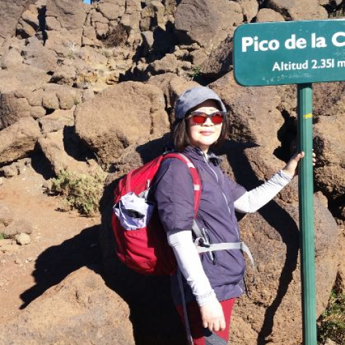Kim steht neben einem Wegweiser beim Wandern auf der Kanareninsel La Palma.